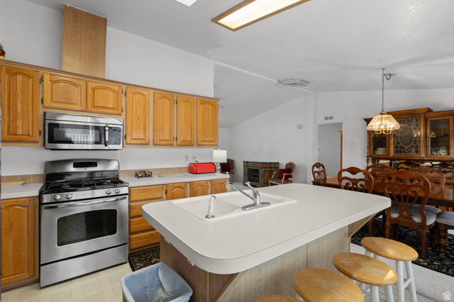 2600 North Hill Field Road, Unit 134 Layton, UT 84041 - Photo 13 of 41 Kitchen featuring a kitchen bar, stainless steel appliances, light countertops, a kitchen island with sink, and lofted ceiling