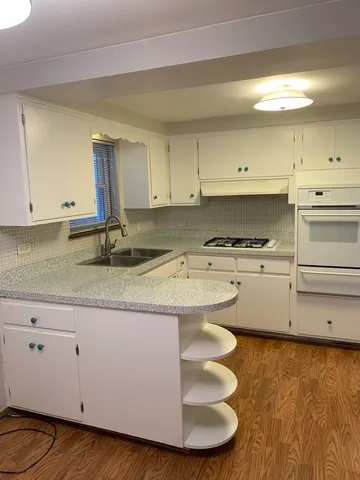 a kitchen with kitchen island granite countertop white cabinets and a sink
