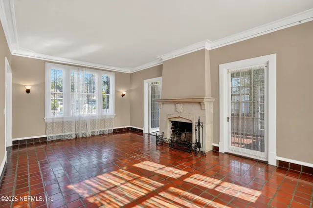 a view of an empty room with window and wooden floor