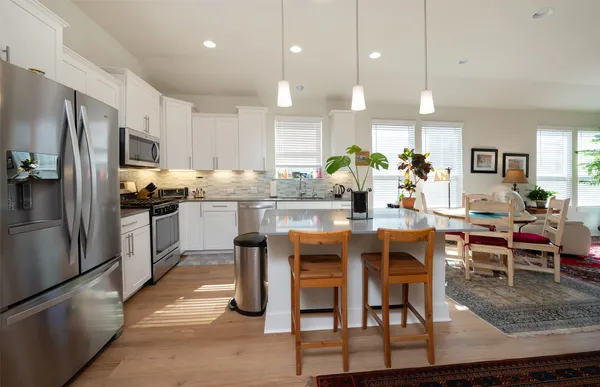 a kitchen with stainless steel appliances kitchen island granite countertop a table chairs and a refrigerator