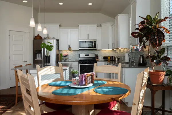 a kitchen with stainless steel appliances granite countertop a dining table and chairs