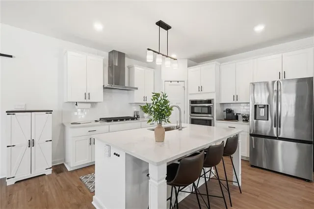 a kitchen with stainless steel appliances a dining table chairs refrigerator and sink