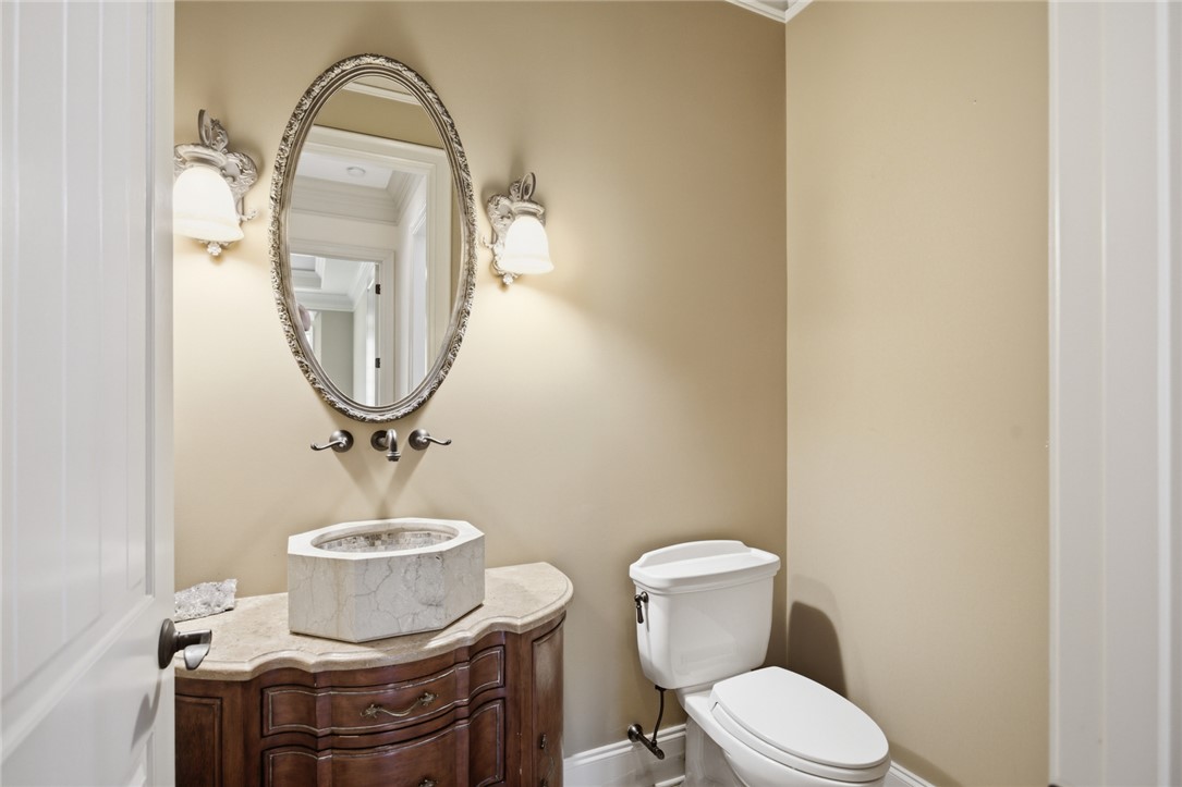 130 River Ridge Road Sunset, SC 29685 - Photo 14 of 47 This powder room showcases a unique stone vessel sink set upon a richly detailed vanity, complemented by an ornate mirror and elegant wall sconces.