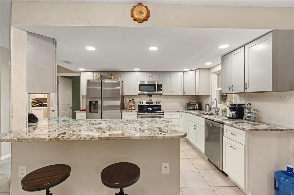 7466 Apache Trail Spring Hill, FL 34606 - Photo 13 of 27 a kitchen with stainless steel appliances granite countertop a sink a stove top oven a counter space and cabinets