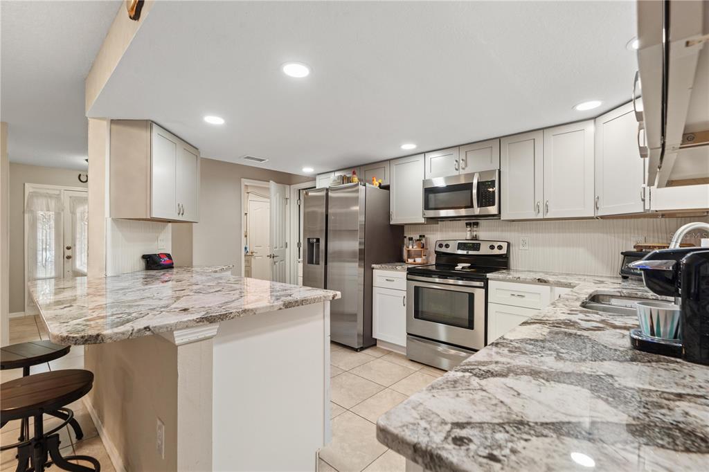 7466 Apache Trail Spring Hill, FL 34606 - Photo 14 of 27 a kitchen with kitchen island granite countertop a stove sink microwave and cabinets