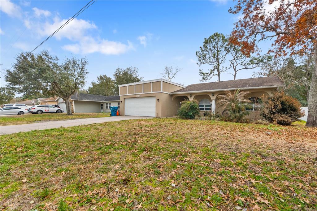 7466 Apache Trail Spring Hill, FL 34606 - Photo 2 of 27 a front view of a house with a garden