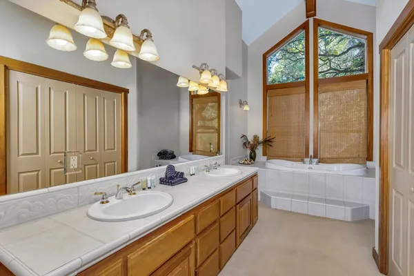 a bathroom with a granite countertop sink a large mirror and a bathtub next to a window