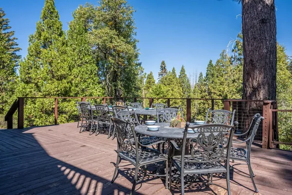 a view of a dinning table and chairs on the deck in front of house