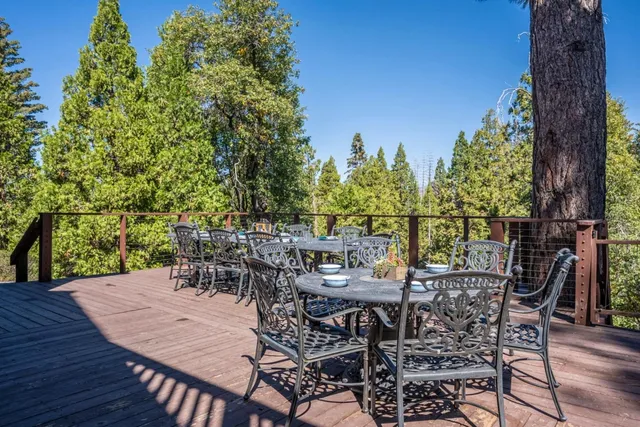 a view of a dinning table and chairs on the deck in front of house