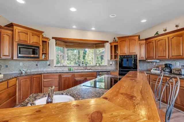 a large kitchen with kitchen island granite countertop a large window and stainless steel appliances