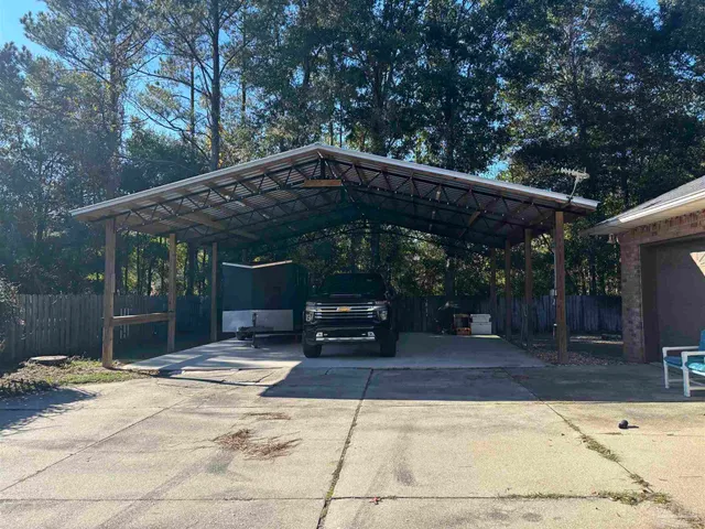 a view of a patio with table and chairs under an umbrella with large trees