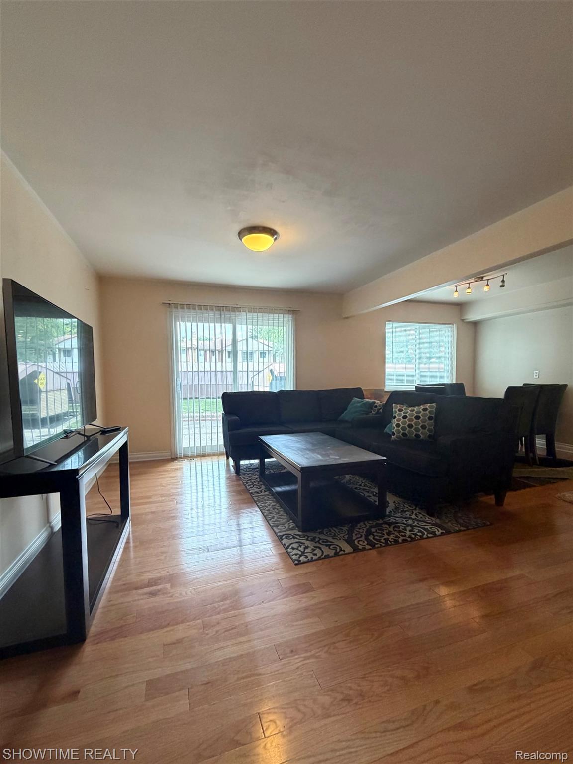 29117 Hayes Road, Unit 3 Warren, MI 48088 - Photo 3 of 14 Hardwood flooring throughout a spacious living area featuring a sliding glass door with vertical blinds