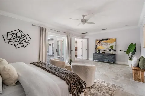 a spacious bedroom with a large bed a chandelier and mirror