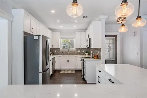 a kitchen with a refrigerator a sink and dishwasher a oven with white cabinets