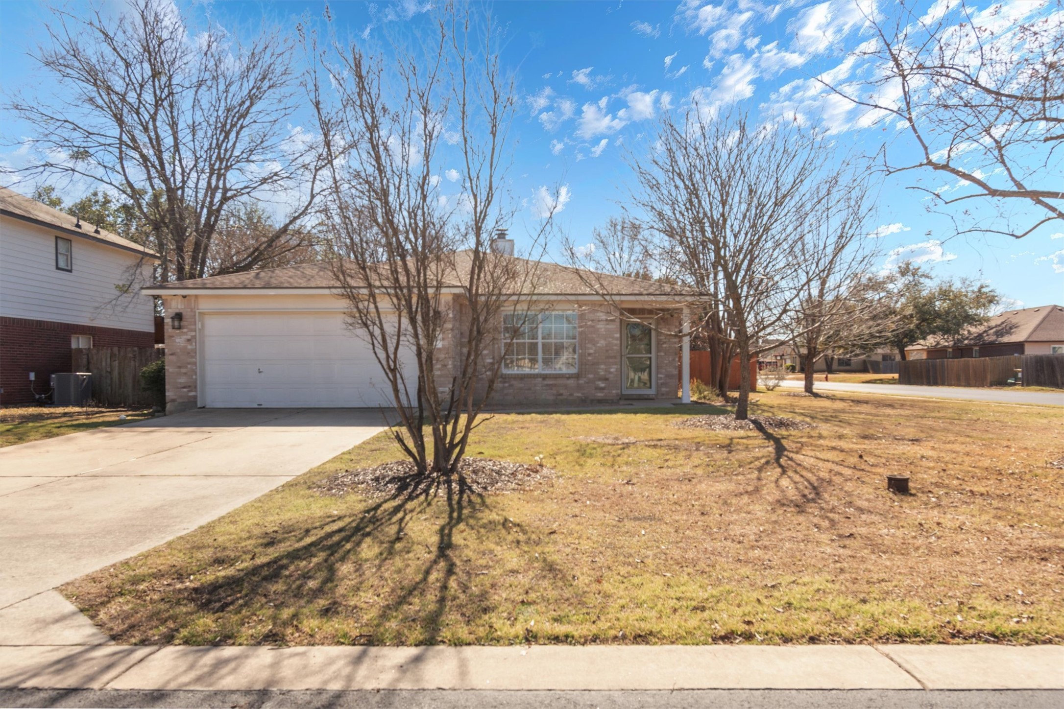 View of front facade with brick siding, driveway, an attached garage, and a chimney