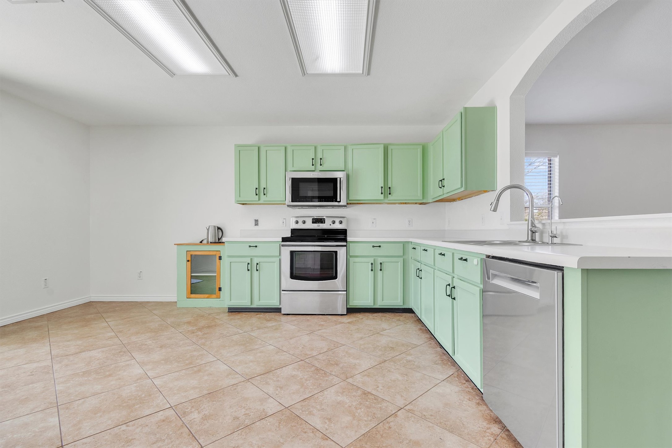 100 Madisons Way Buda, TX 78610 - Photo 11 of 30 Kitchen with stainless steel appliances, light countertops, green cabinetry, and light tile patterned flooring