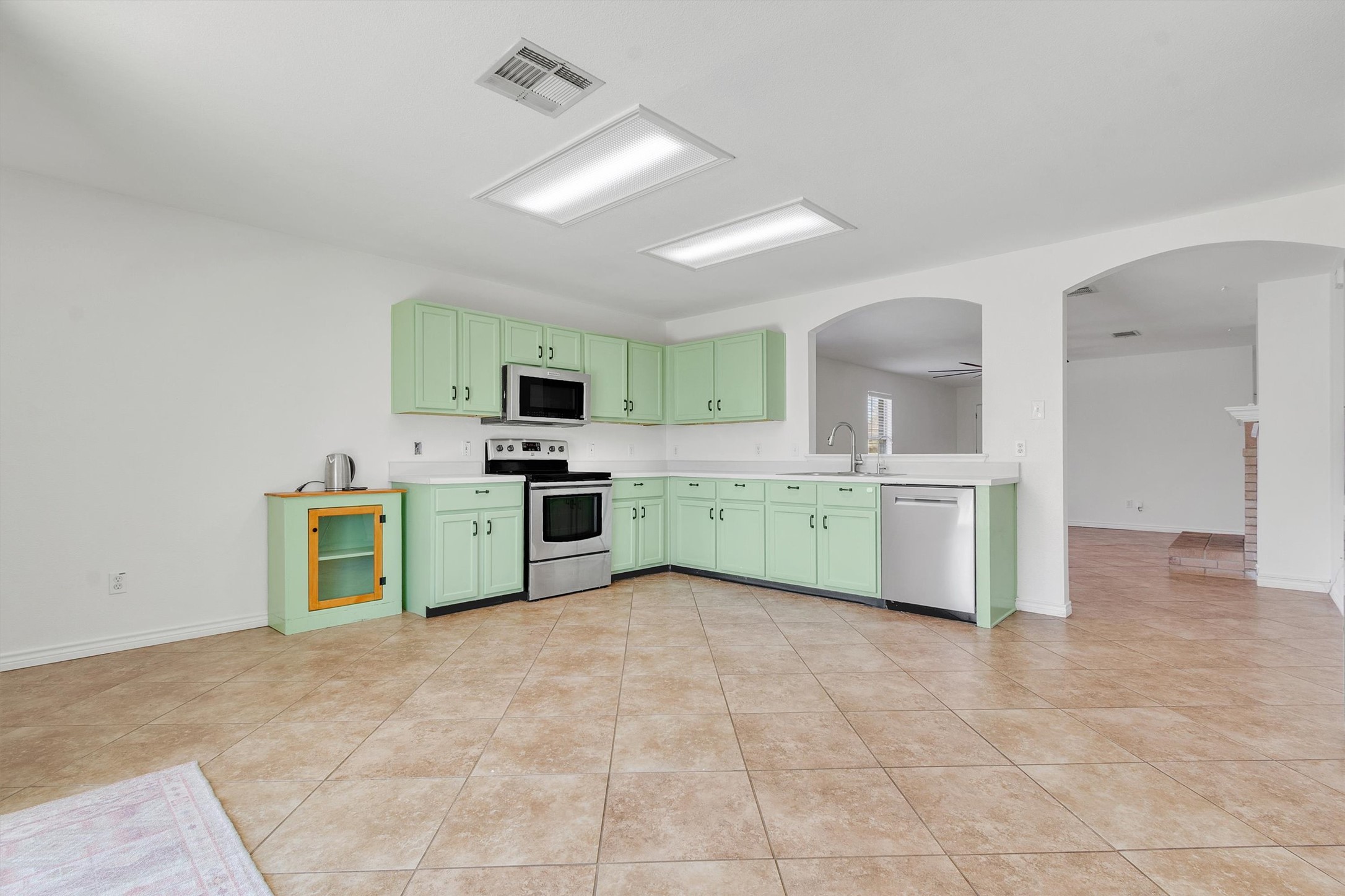 100 Madisons Way Buda, TX 78610 - Photo 30 of 30 Kitchen with arched walkways, stainless steel appliances, light countertops, green cabinets, and open floor plan