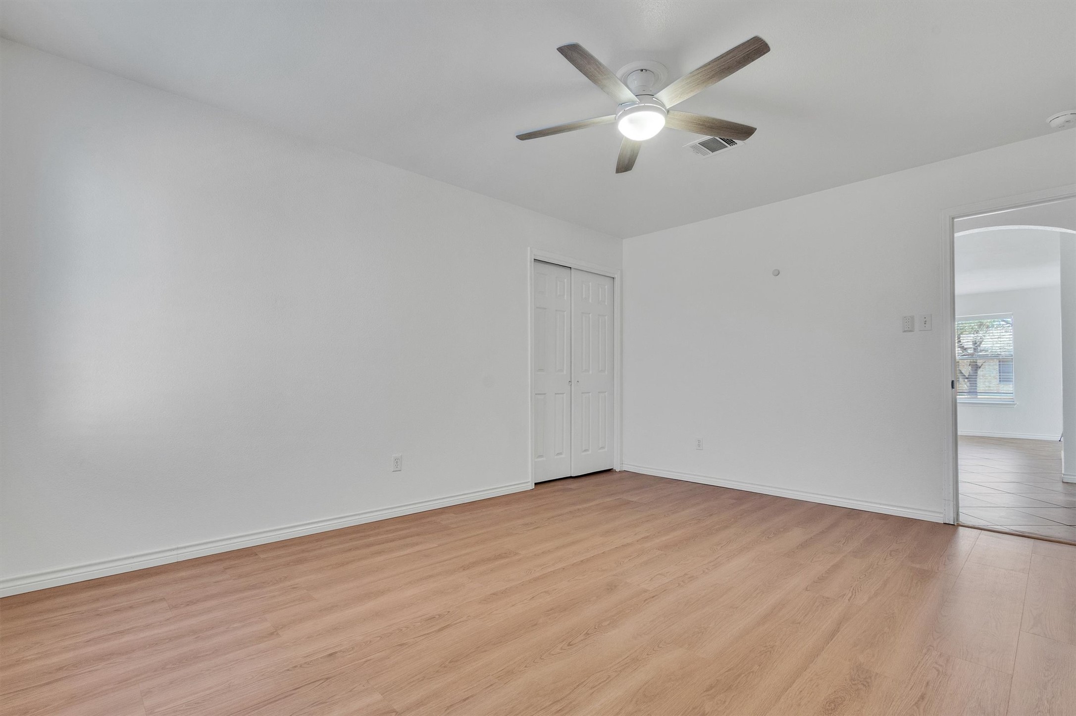 100 Madisons Way Buda, TX 78610 - Photo 23 of 30 Unfurnished bedroom featuring arched walkways, light wood-type flooring, a ceiling fan, and a closet