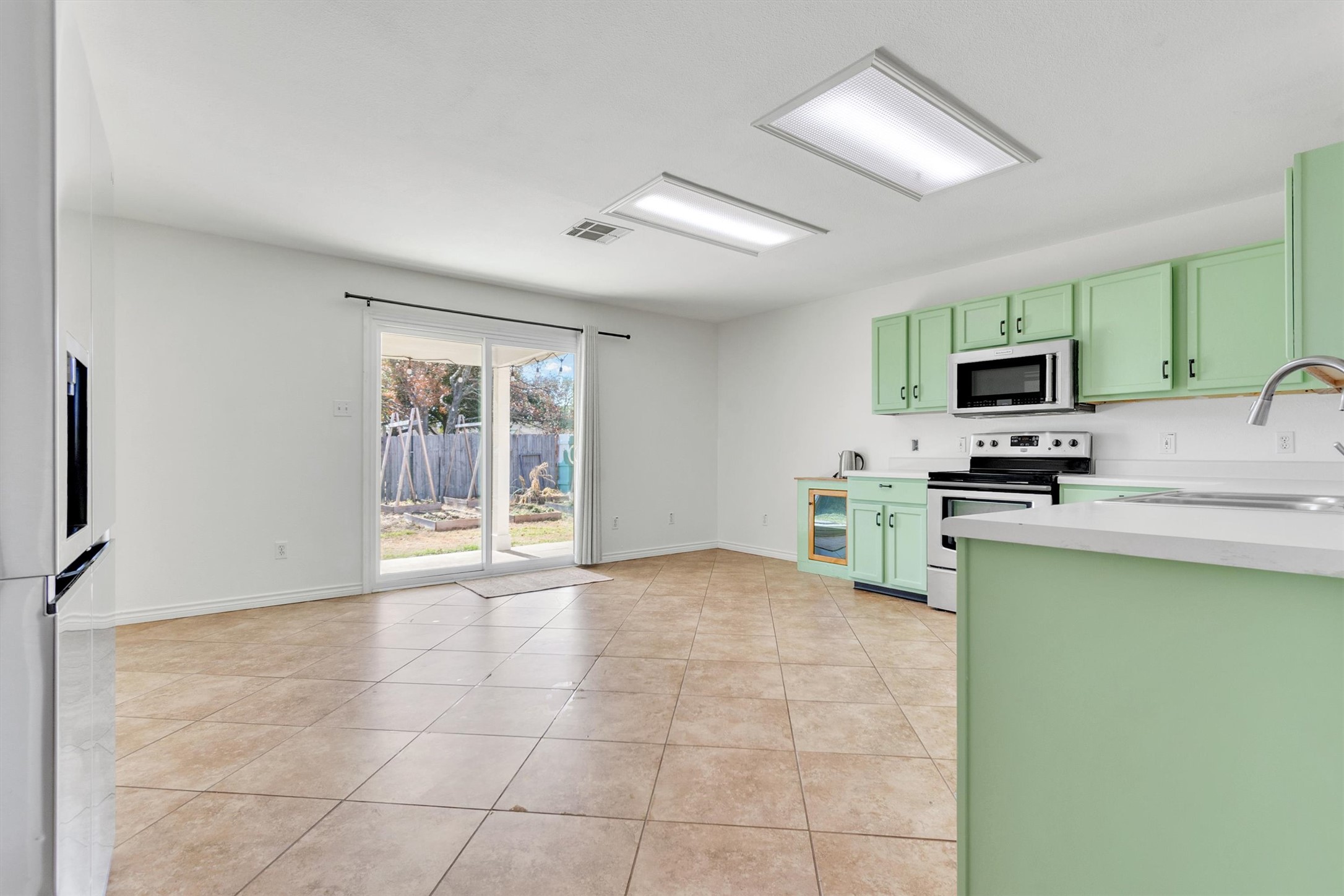 100 Madisons Way Buda, TX 78610 - Photo 9 of 30 Kitchen featuring green cabinetry, electric stove, light countertops, light tile patterned floors, and paneled built in refrigerator