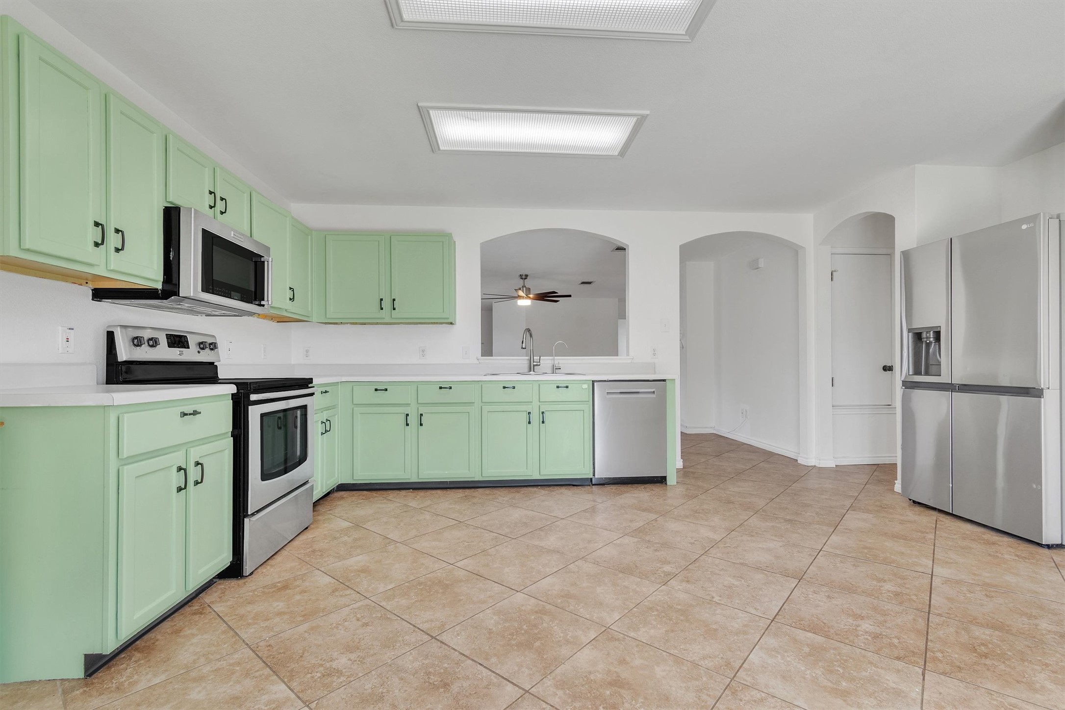 100 Madisons Way Buda, TX 78610 - Photo 10 of 30 Kitchen featuring green cabinets, stainless steel appliances, light countertops, arched walkways, and a ceiling fan