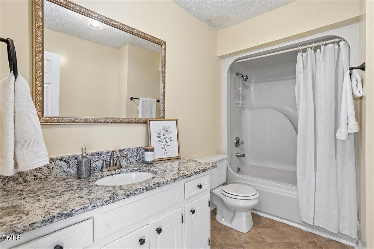 1334 Langdon Road Angier, NC 27501 - Photo 35 of 36 a bathroom with a granite countertop sink toilet a mirror and shower