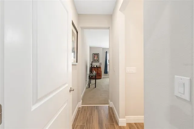 a view of a hallway with wooden floor and a bathroom