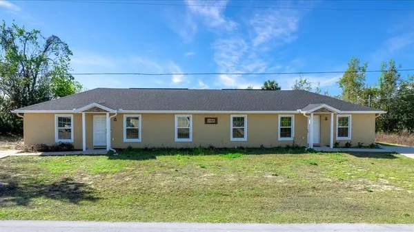 a front view of house with yard and trees in the background