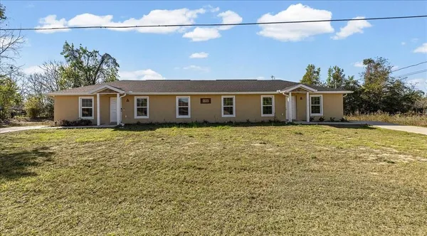 a front view of house with yard and trees in the background