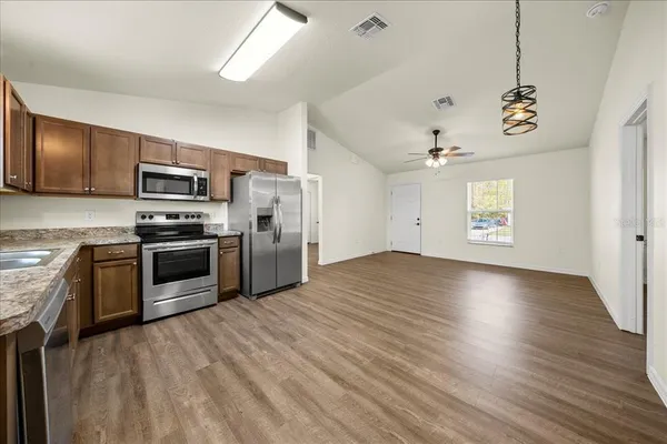 an empty room with wooden floor and ceiling fan