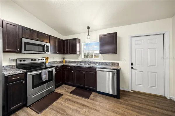 a kitchen with stainless steel appliances granite countertop a stove microwave and sink