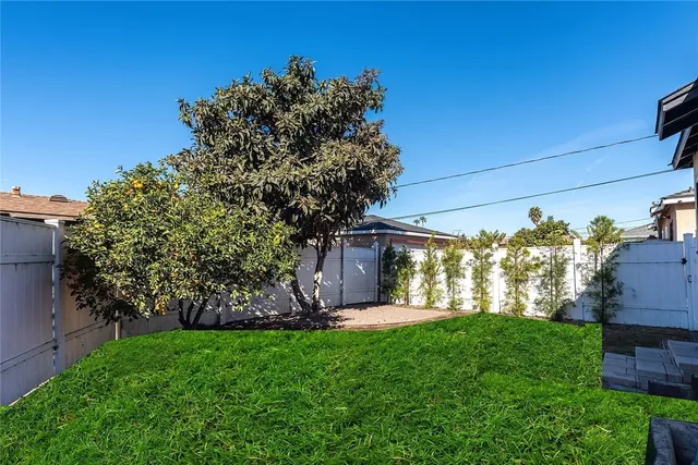 a view of a house with a big yard potted plants and large tree