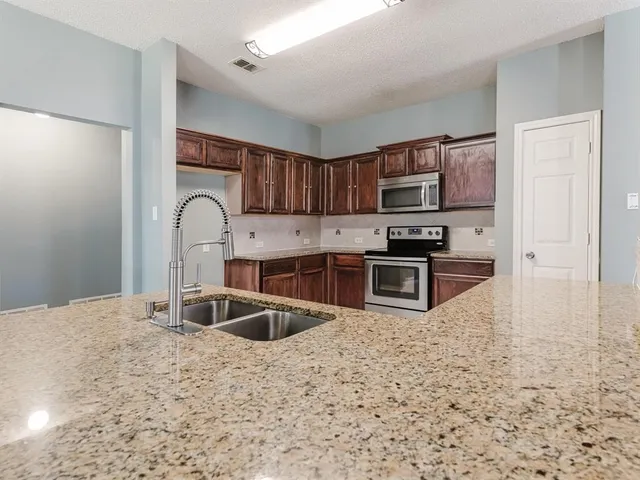 a large kitchen with kitchen island a sink stainless steel appliances and cabinets