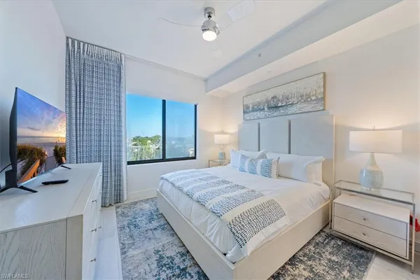 a bedroom with a bed a dresser and potted plants