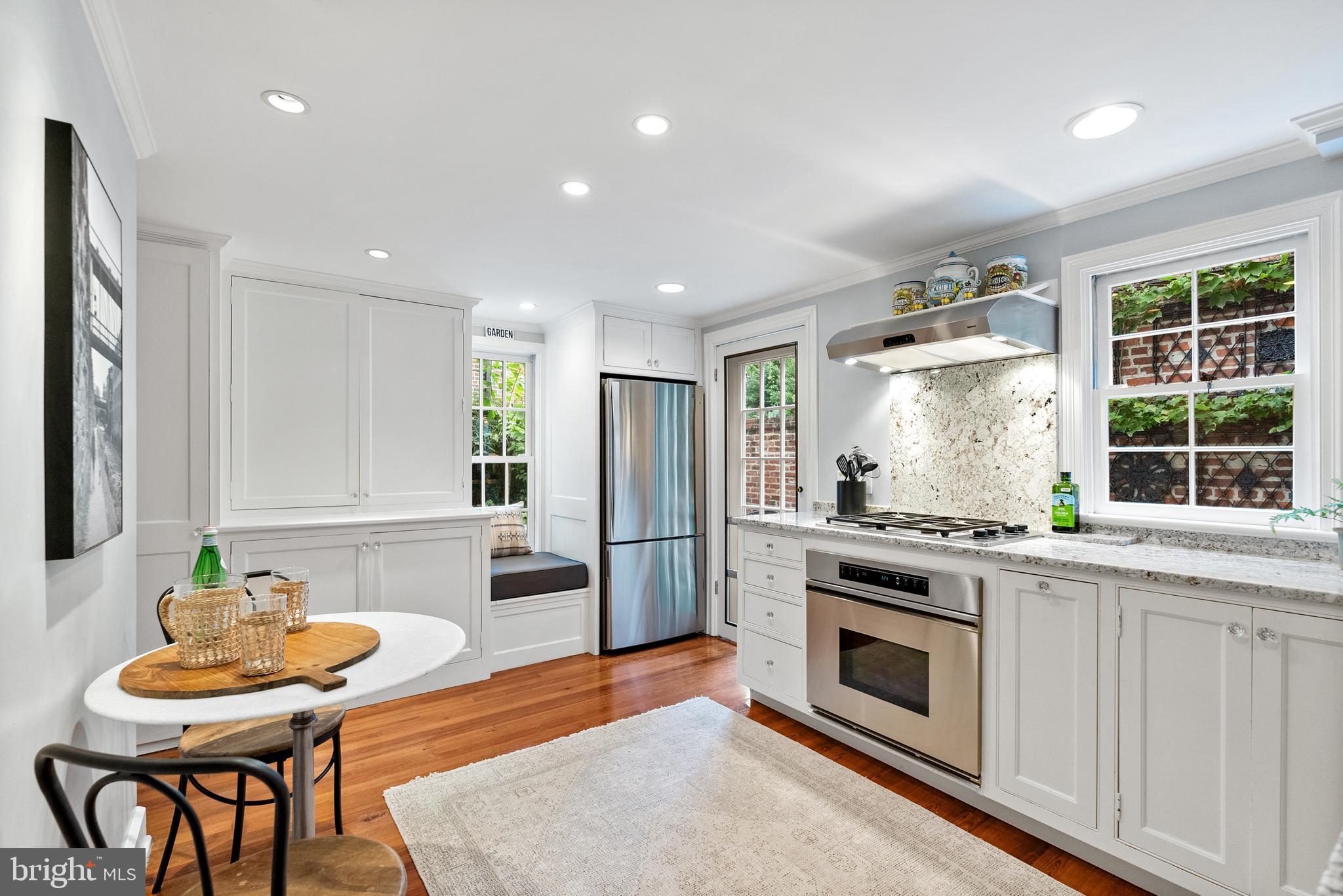3403 O Street Northwest Washington, DC 20007 - Photo 10 of 35 a kitchen with stainless steel appliances kitchen island granite countertop a stove a sink a refrigerator and a dining table with wooden floor