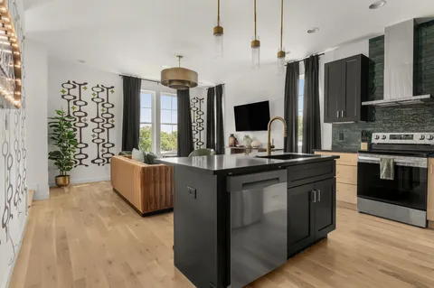 a kitchen with stainless steel appliances granite countertop a refrigerator a sink and a stove