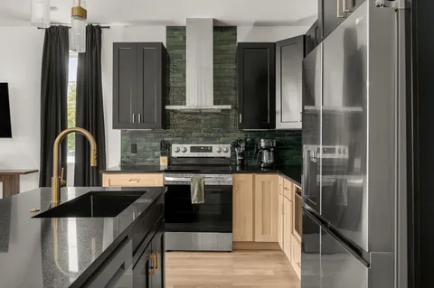 a kitchen with stainless steel appliances kitchen island granite countertop a refrigerator a sink and wooden cabinets