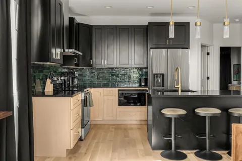 a kitchen with stainless steel appliances kitchen island granite countertop a refrigerator and a stove top oven