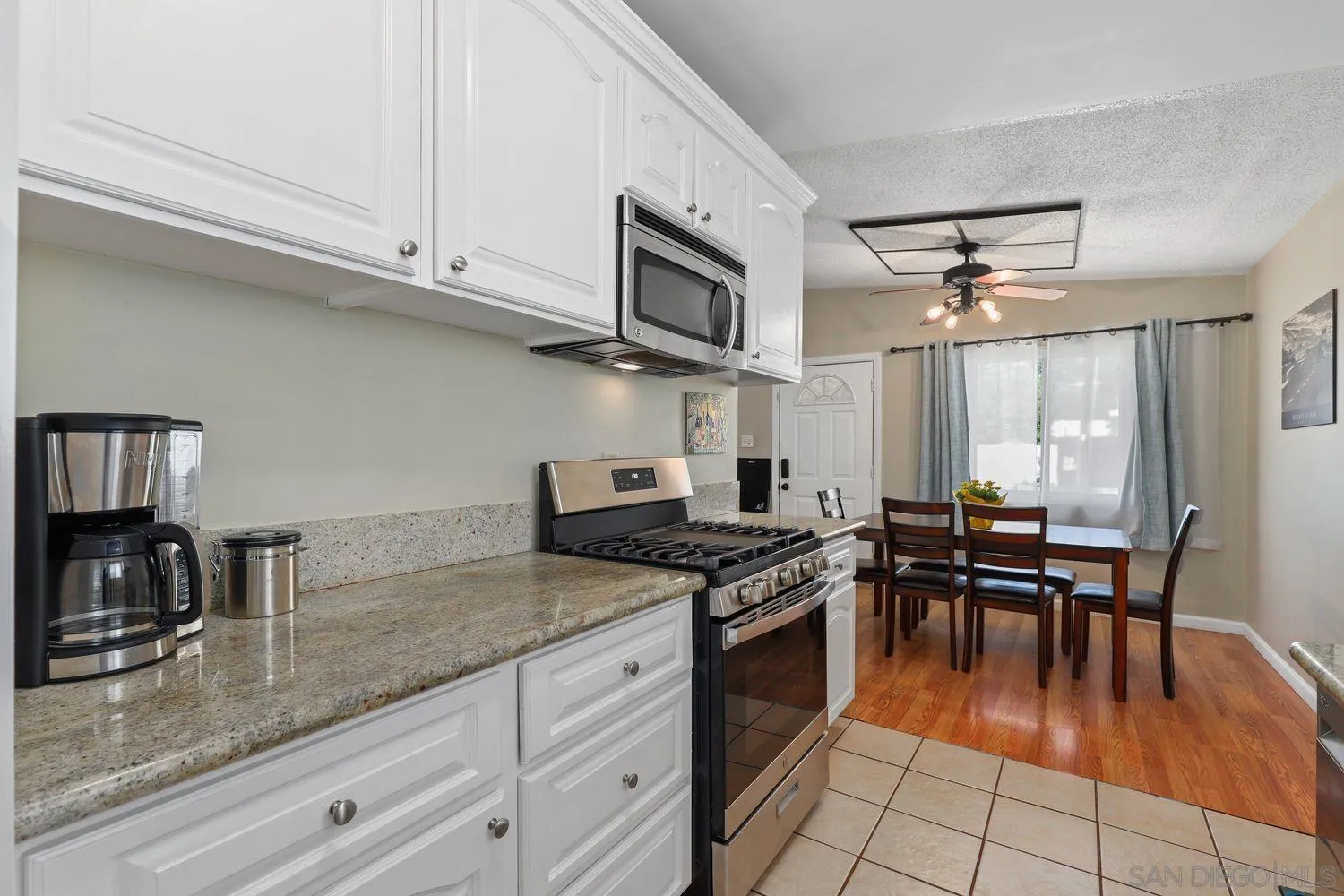 8619 Harness Street Spring Valley, CA 91977 - Photo 8 of 23 a kitchen with granite countertop a stove a sink dishwasher and white cabinets with wooden floor