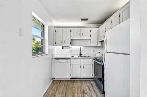 a kitchen with a sink appliances cabinets and a window
