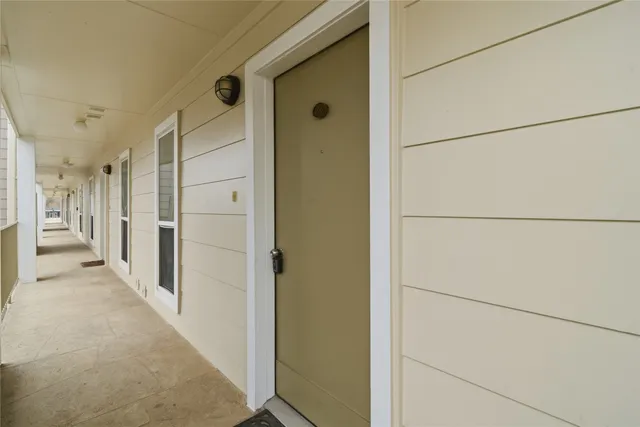 a view of a hallway to a room with furniture and windows
