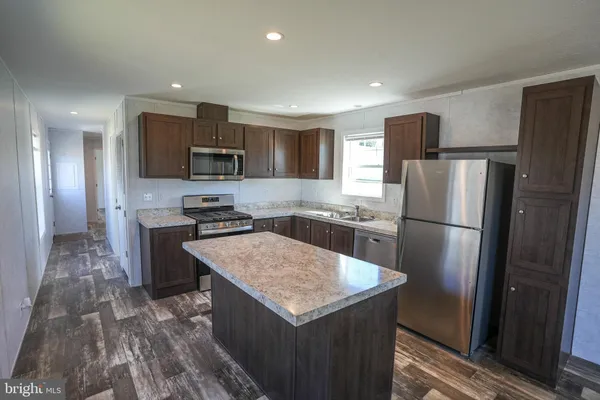 a kitchen with stainless steel appliances granite countertop a refrigerator a stove a sink dishwasher and a refrigerator with wooden floor