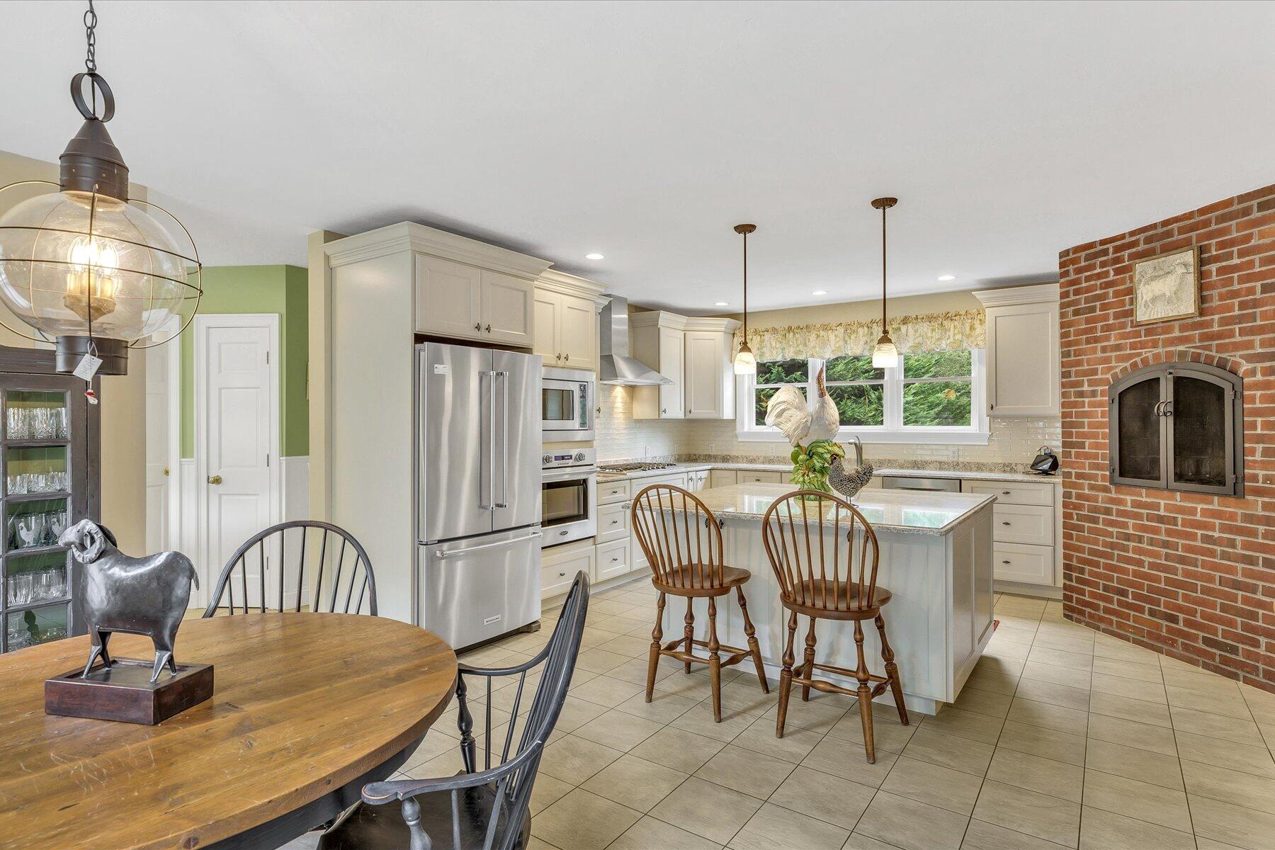 663 Crowells Bog Road Brewster, MA 02631 - Photo 9 of 46 a kitchen with granite countertop a table chairs a sink dishwasher refrigerator and cabinets
