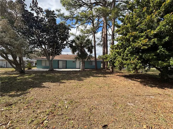 a front view of a house with a yard and covered with trees