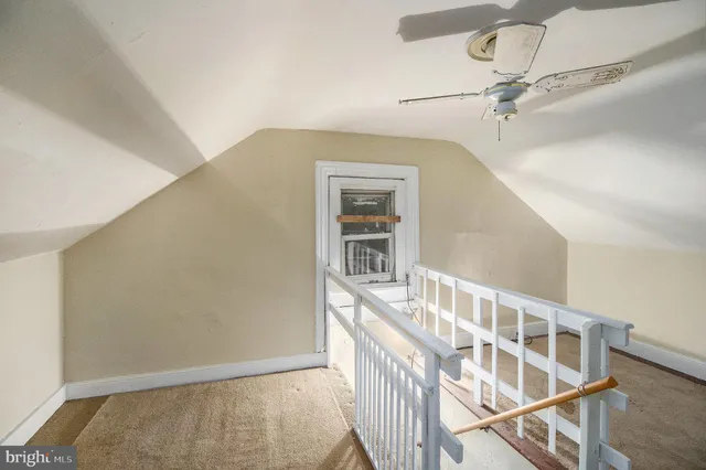 a view of staircase with white walls and fan