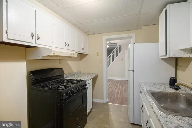 a kitchen with granite countertop a sink stove and cabinets