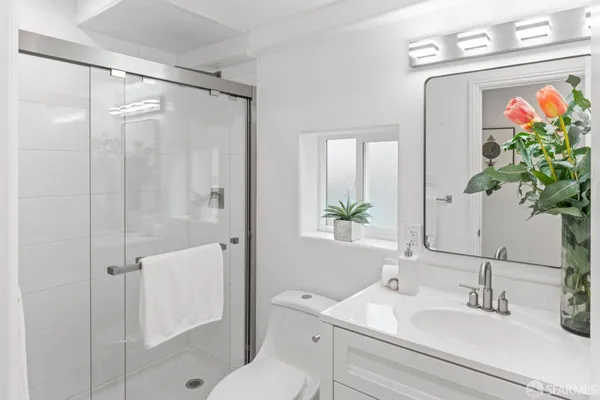 a bathroom with a shower sink vanity and toilet
