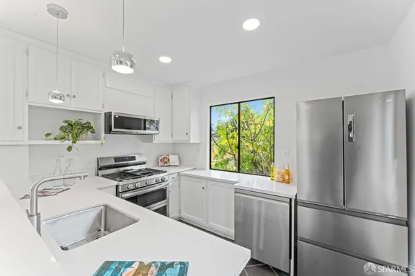 a kitchen with stainless steel appliances a stove a refrigerator sink and white cabinets