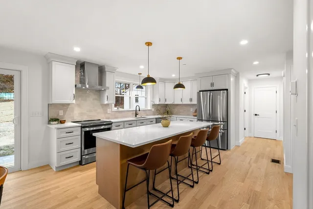 a kitchen with stainless steel appliances a stove a sink a refrigerator and chairs