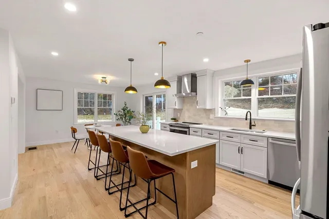 a kitchen with stainless steel appliances granite countertop a stove a sink dishwasher and a refrigerator with wooden floor