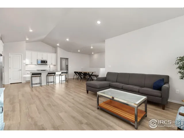a living room with furniture and kitchen view with wooden floor